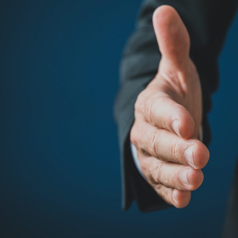 Hand of a businessman reaching in handshake